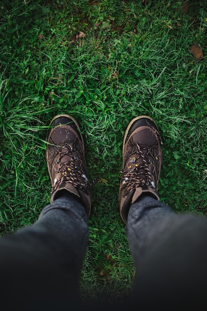 Punto di vista dell'uomo che indossa scarpe da trekking sull'erba al mattino Tiro ad alto angolo Campagna