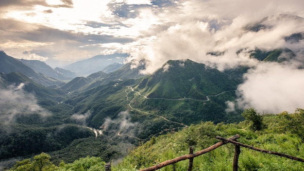 Punto di vista della montagna fantastica nella nebbia con strada rurale