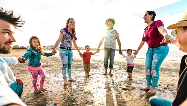 Punto di vista di giovani famiglie che ballano in spiaggia su un anello intorno allo stile roseo