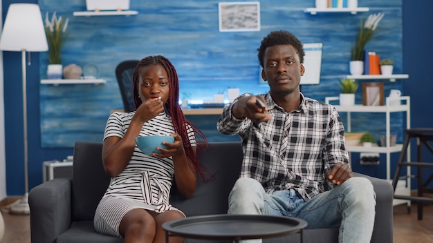 Punto di vista di una coppia nera che guarda la televisione sul divano di casa