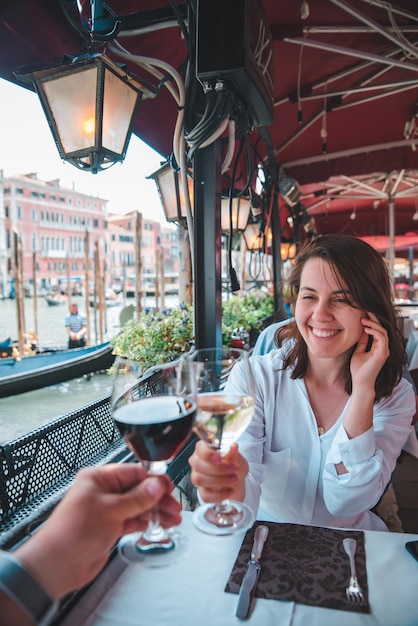 Punto di vista in prima persona coppia al bar all'aperto bevendo vino donna sorridente canal grande venezia