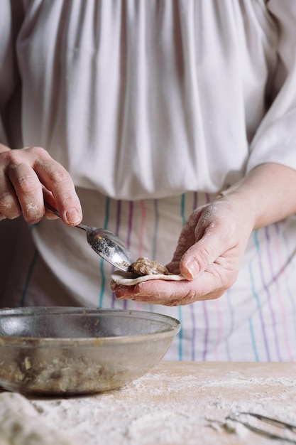 Punto di vista medio anteriore delle mani della donna che fanno gli gnocchi di carne