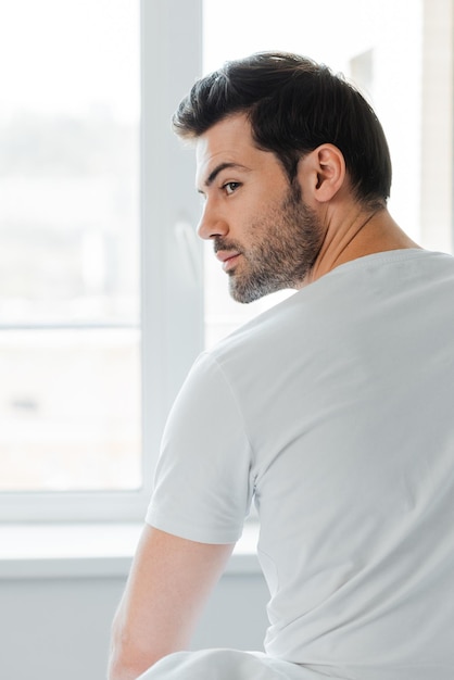 Punto di vista posteriore dell'uomo che distoglie lo sguardo vicino alla finestra a casa