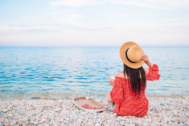 Punto di vista posteriore della donna sulla spiaggia sul picnic che esamina il mare