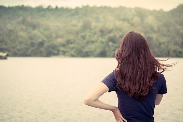 Punto di vista posteriore della ragazza che sta davanti alla riva del fiume nel tono di colore d&#39;annata