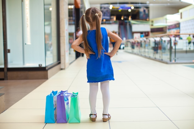 Punto di vista posteriore della ragazza di modo con i pacchetti nel centro commerciale