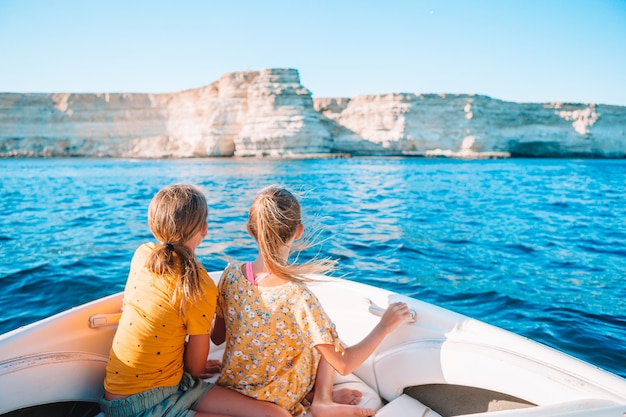 Punto di vista posteriore delle bambine sveglie che godono della navigazione sulla barca nel mare aperto