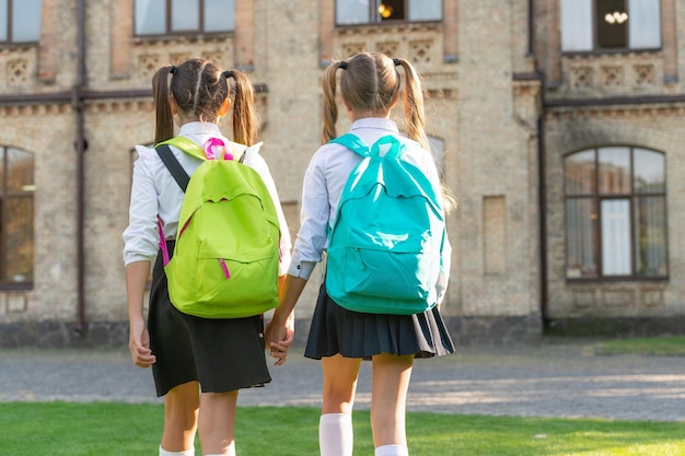 Punto di vista posteriore di due studentesse con lo zaino della scuola che camminano insieme lo spazio della copia all'aperto