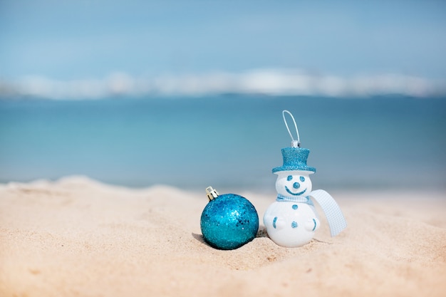 Pupazzo di neve in un cappello blu e palla blu di Natale