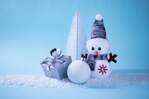 Pupazzo di neve, regalo, albero di Natale, palla di Natale su neve bianca su sfondo turchese