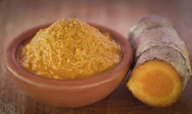 Purè di curcuma in una ciotola di argilla su superficie di legno