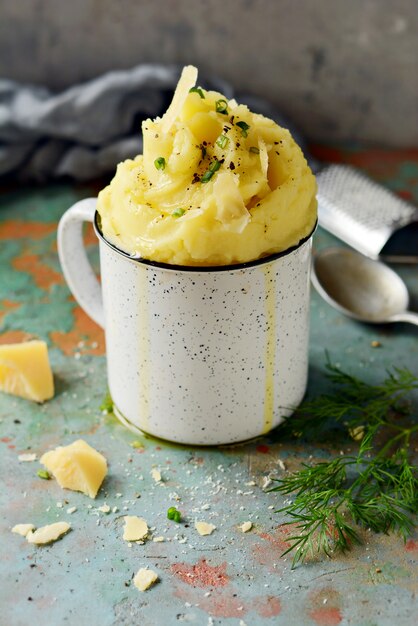 Purè di patate con burro e olio d'oliva, verdure e fette di parmigiano su uno sfondo grigio