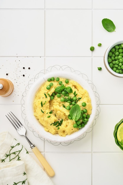 Purè di patate con burro, piselli, cipolle, basilico in una ciotola bianca