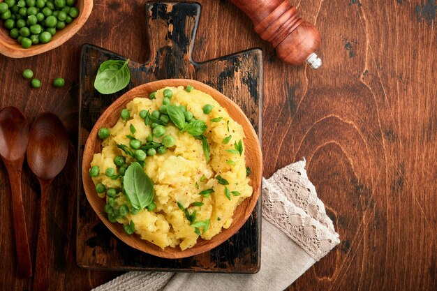 Purè di patate con burro, piselli, cipolle, basilico in una ciotola bianca