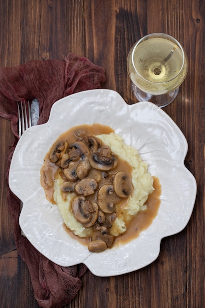 Purè di patate con funghi e salsa sul piatto bianco