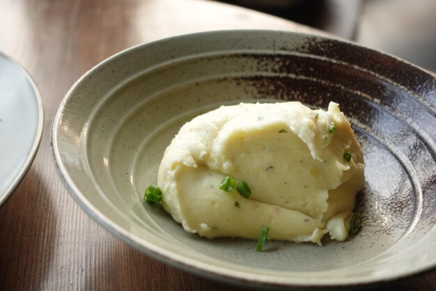 Purè di patate in una ciotola su tavola rustica in legno