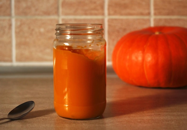 Purea di zucca baby in vasetto di vetro con cucchiaio e zucca fresca