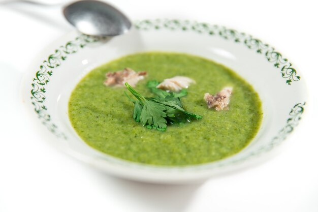 Purea di zuppa di broccoli, patate decorate con prezzemolo e carne su sfondo bianco, fuoco selettivo.