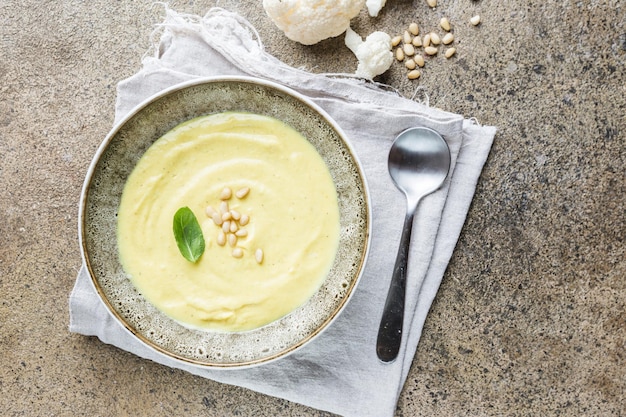 Purea di zuppa di cavolfiore su uno sfondo di pietra, vista dall'alto. Concetto di cibo sano vegetariano