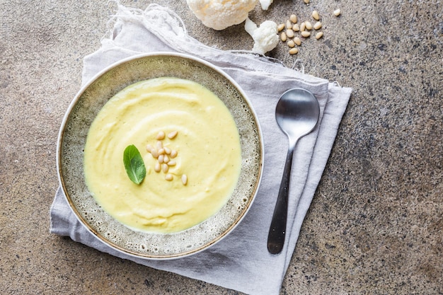 Purea di zuppa di cavolfiore su uno sfondo di pietra, vista dall'alto. Concetto di cibo sano vegetariano