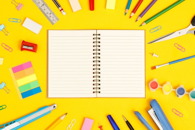 Quaderni e accessori di cancelleria vista dall'alto che studiano in biblioteca a scuola sfondo giallo idea educazione