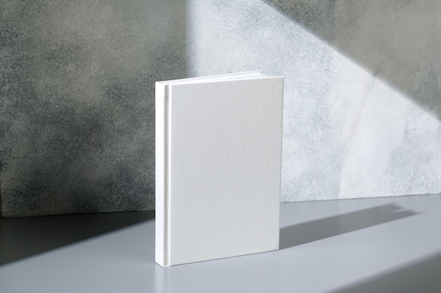 Quaderno bianco con copertina rigida su sfondo grigio