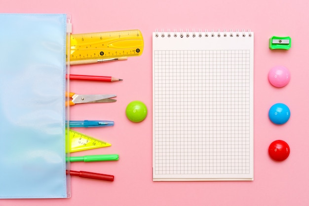 Quaderno scolastico e vari articoli per ufficio per tornare al concetto di scuola su sfondo rosa brillante