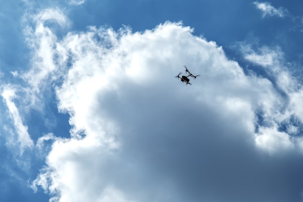 Quadrocopter volante su nuvole e cielo blu