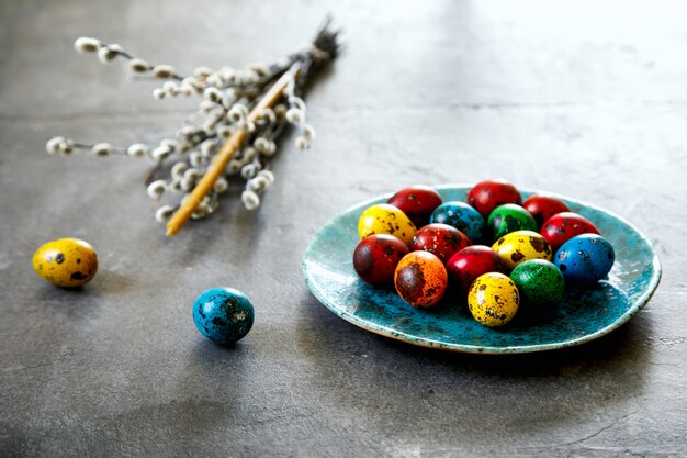 Quaglie di uova di Pasqua su piatti con candele e salici