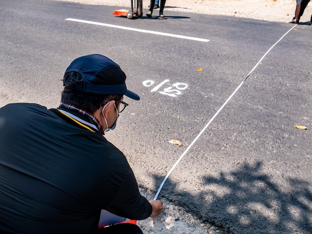 qualcuno misura la larghezza di una strada asfaltata senza indossare indumenti di sicurezza