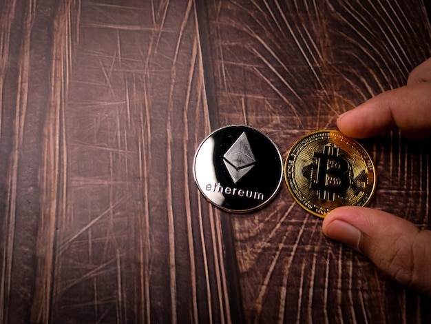 Qualcuno tiene in mano un bitcoin dorato con a lato una moneta crittografica digitale ethereum d'argento