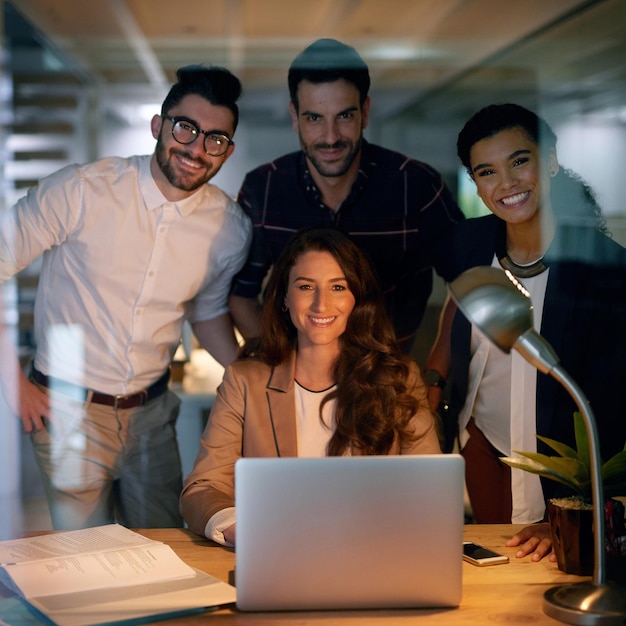 Quando ami il tuo lavoro non guardi l'orologio Ritratto di un gruppo di uomini d'affari che usano un laptop mentre fanno gli straordinari in ufficio