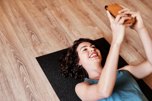 Quando il tuo dispositivo tascabile diventa il tuo personal trainer Inquadratura di una giovane donna che usa uno smartphone durante una sessione di yoga