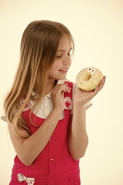 Quanto sono cattivi i dolci per i tuoi bambini La bella faccia sorridente della ragazza tiene una ciambella dolce Alla ragazza piacciono i dolci come le ciambelle Evita le ricompense con lo zucchero Il bambino viene premiato per il buon comportamento con le prelibatezze zuccherate