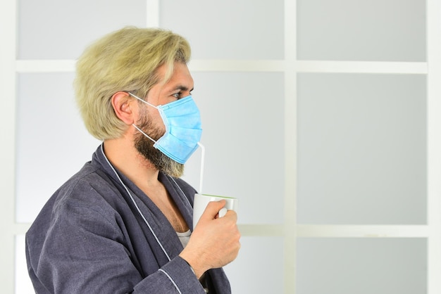 Quarantena pandemica Maschera antivirus Maschere per proteggere dai virus L'uomo indossa una maschera per proteggersi dalle infezioni virali l'uomo beve caffè in maschera medica mattina a casa sull'autoisolamento del coronavirus