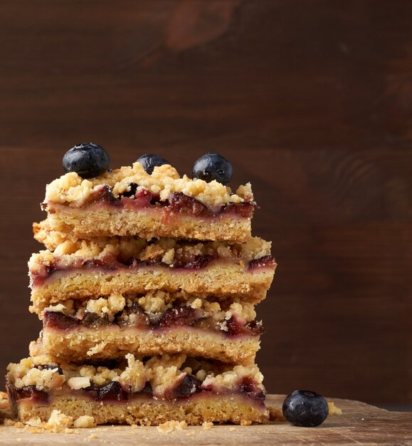 Quare fette di crumble al forno torta con prugna blu su una tavola di legno