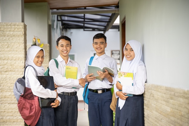 Quattro adolescenti in uniforme della scuola media erano in fila mentre trasportavano libri e un laptop