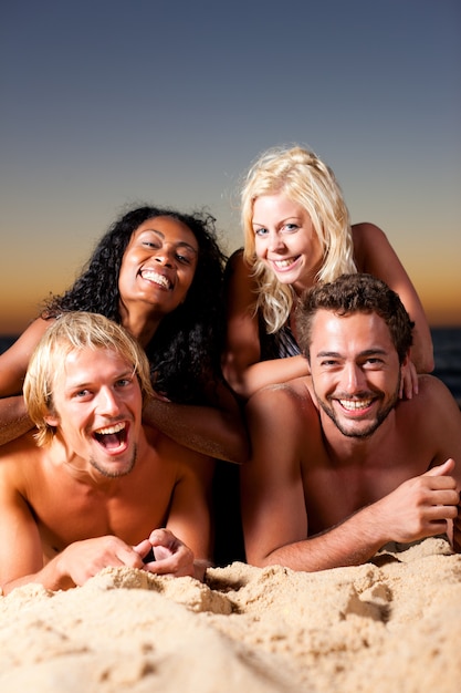 Quattro amici in spiaggia con il tramonto