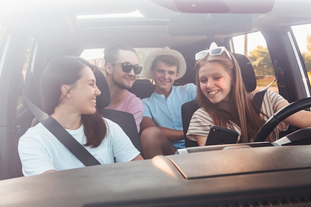 Quattro amici nella navigazione per auto sul telefono. viaggio su strada