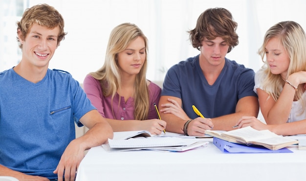 Quattro amici seduti al tavolo e studiano