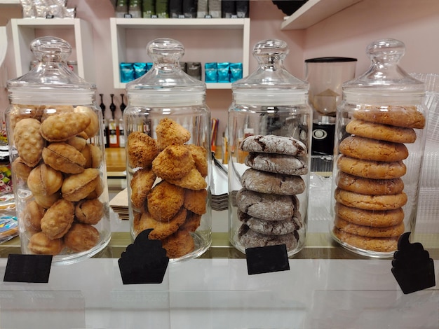 Quattro barattoli di diversi tipi di biscotti in una finestra di un caffè in vendita