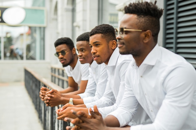 Quattro bei giovani uomini africani in camicie bianche