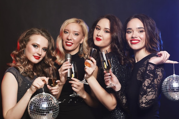 Quattro belle ragazze alla moda che cantano al karaoke al club