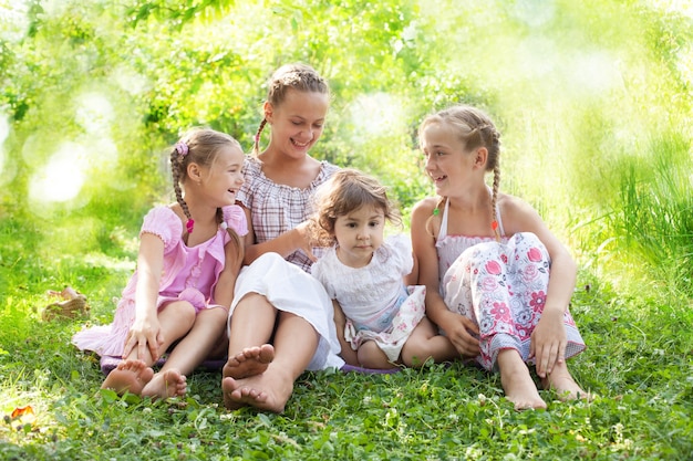 Quattro belle ragazze sedute sull'erba in giardino e sorridenti