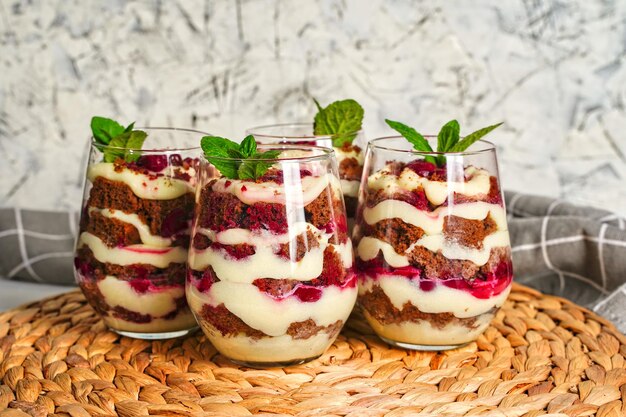 Quattro bicchieri trasparenti con dessert dolce al cioccolato fondente e crema bianca La torta è decorata con una torta porzionata di compleanno in foglia di menta