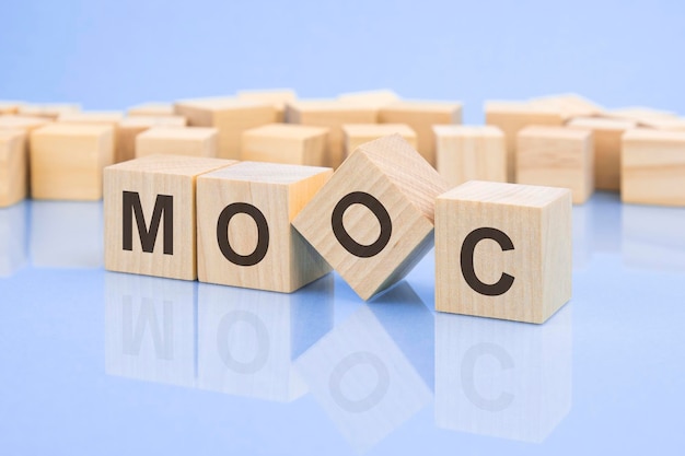Quattro blocchi di legno con le lettere MOOC sulla superficie luminosa di un tavolo lilla pallido la scritta sui cubi viene riflessa dalla superficie MOOC abbreviazione di corso online aperto di massa