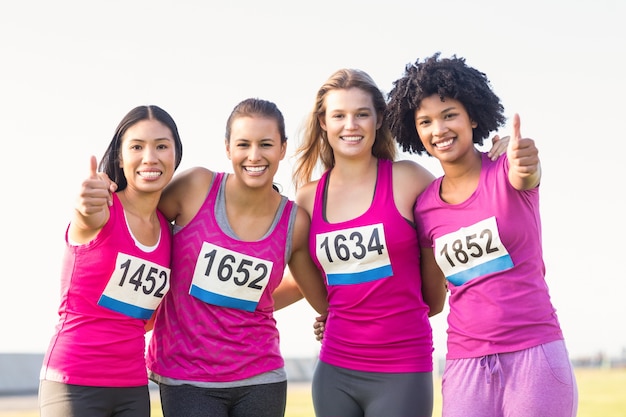 Quattro corridori sorridenti che sostengono la maratona del cancro al seno