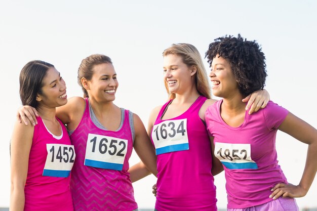 Quattro corridori sorridenti che sostengono la maratona del cancro al seno