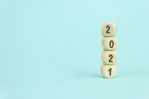 Quattro cubi giocattolo in legno disposti in verticale su sfondo blu con testo 2021, crescita aziendale e concetto di gestione.