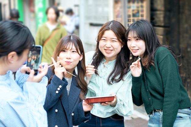 Quattro donne che mangiano takoyaki mentre camminano